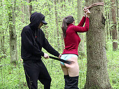 Whipping a Belt of a sub woman strapped to a Tree in a Dense Forest