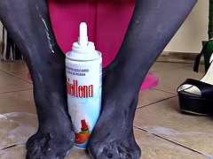 Brunette in pantyhose gives footjob to a tube of cream