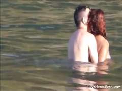Aroused couple having some fun in the water at the beach
