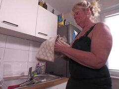 Old blonde woman is fucking herself in the kitchen